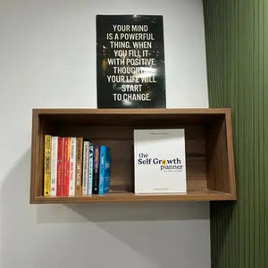 Wooden shelf with books and a motivational poster on a wall.